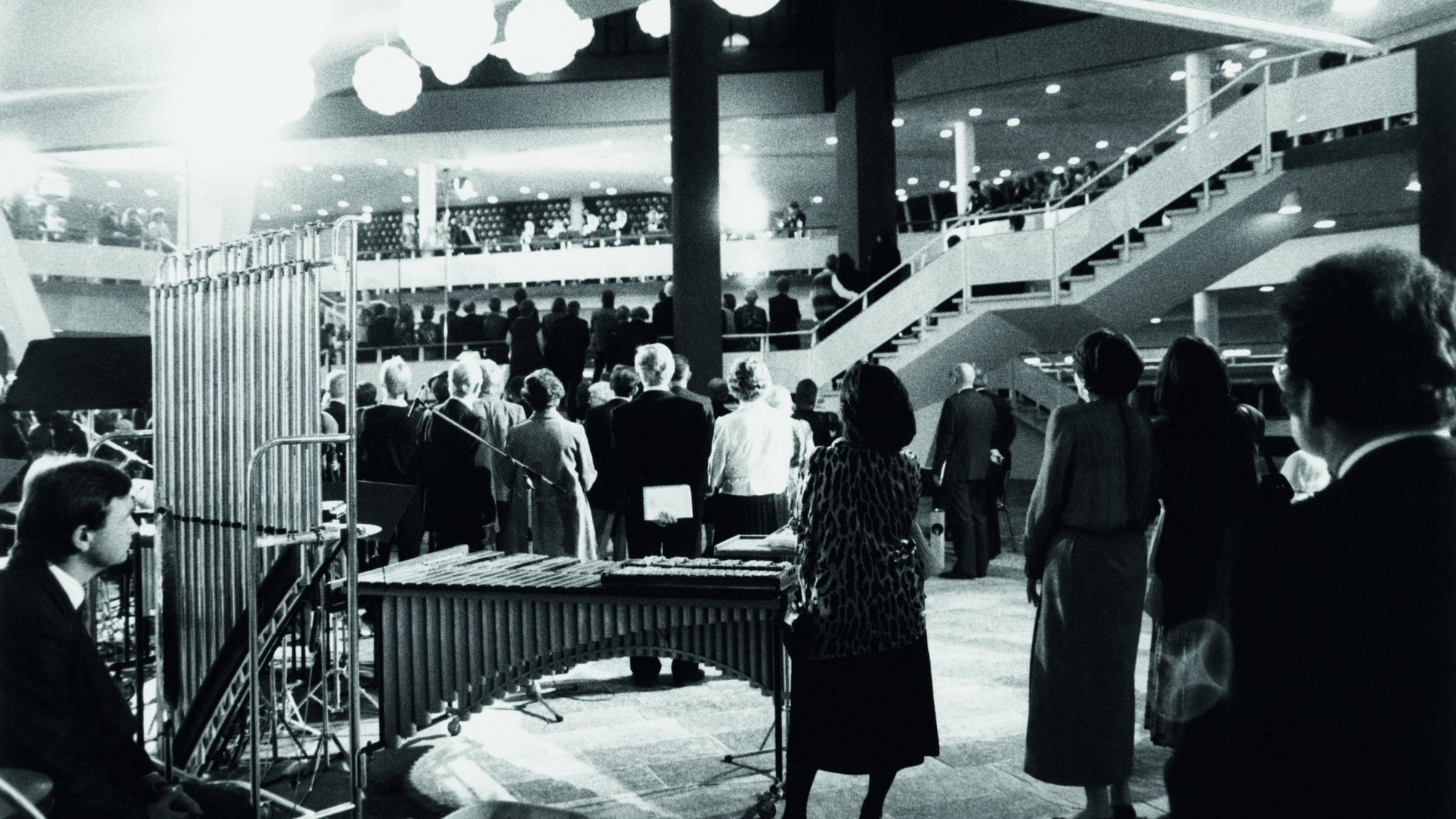 Schwarz-weiß-Foto vom Foyer des Kammemusiksaals mit Gästen und Musikinstrumenten