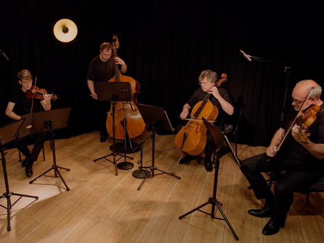 Five musicians in a semicircle in front of a black background