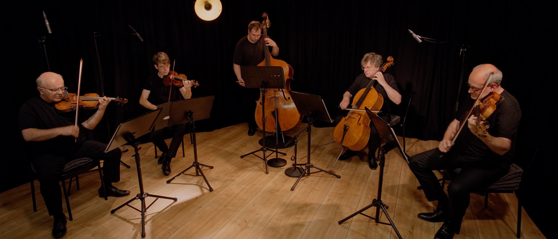 Five musicians in a semicircle in front of a black background
