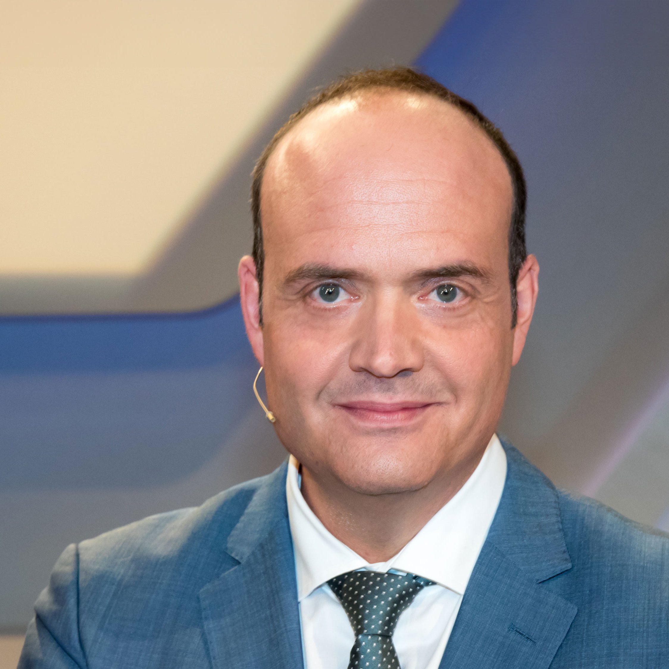 Robin Alexander in a suit in front of a neutral studio background