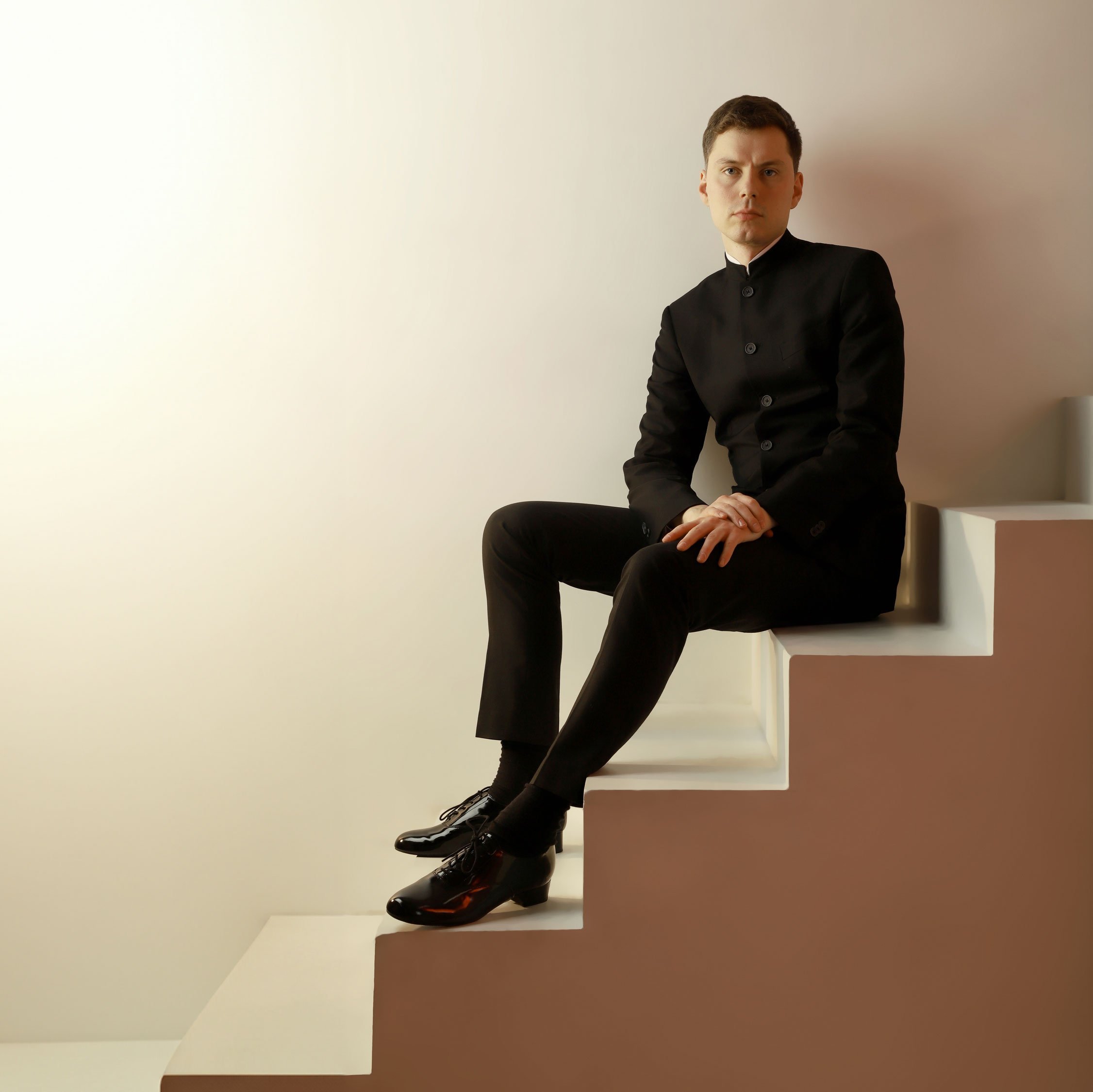 Richard Gowers sits on a staircase in a suit