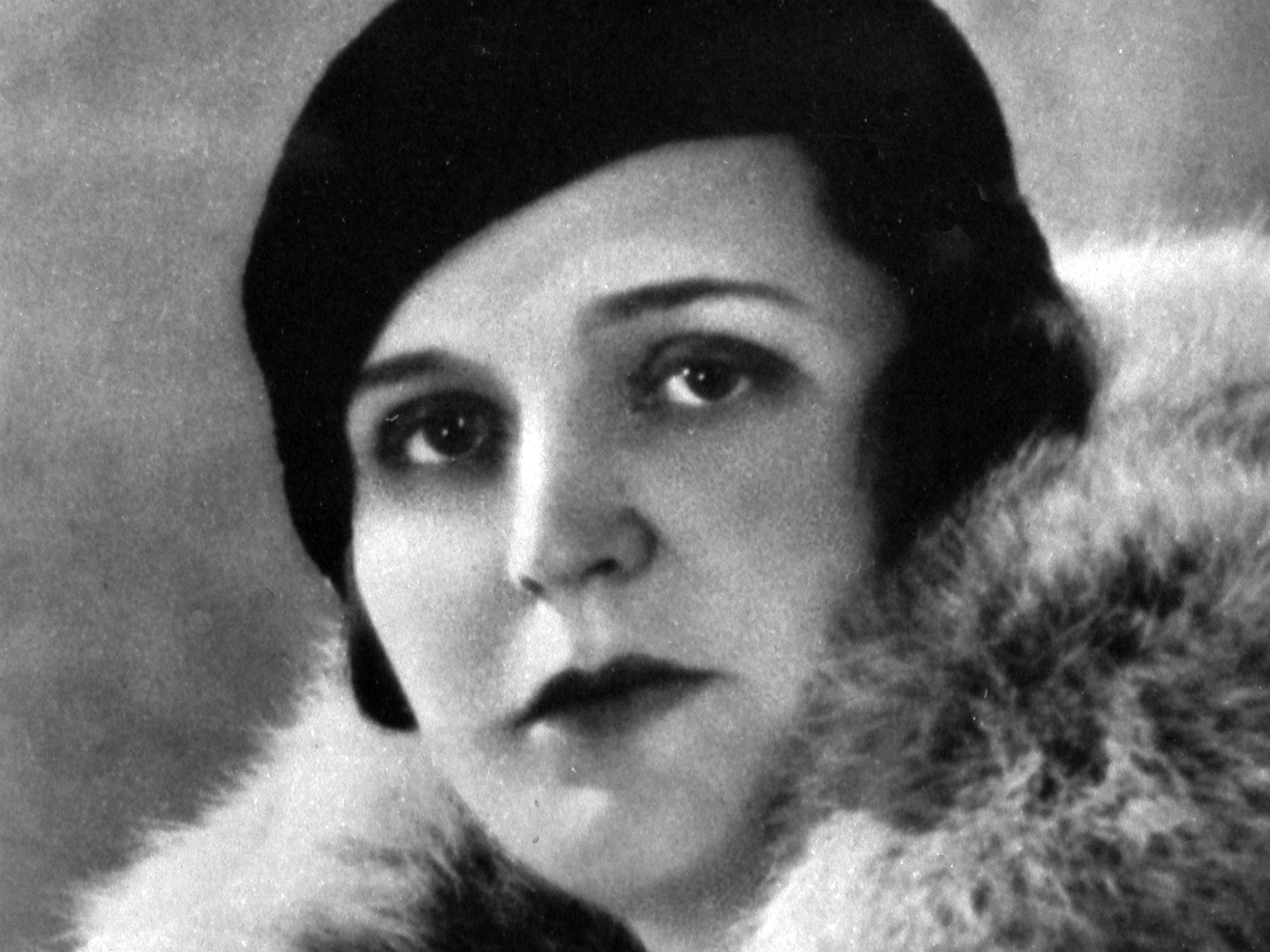 Black and white portrait of Germaine Tailleferre. She is wearing a dark hat and a coat with a lavish fur collar. Her expression is serious and she is looking directly into the camera.