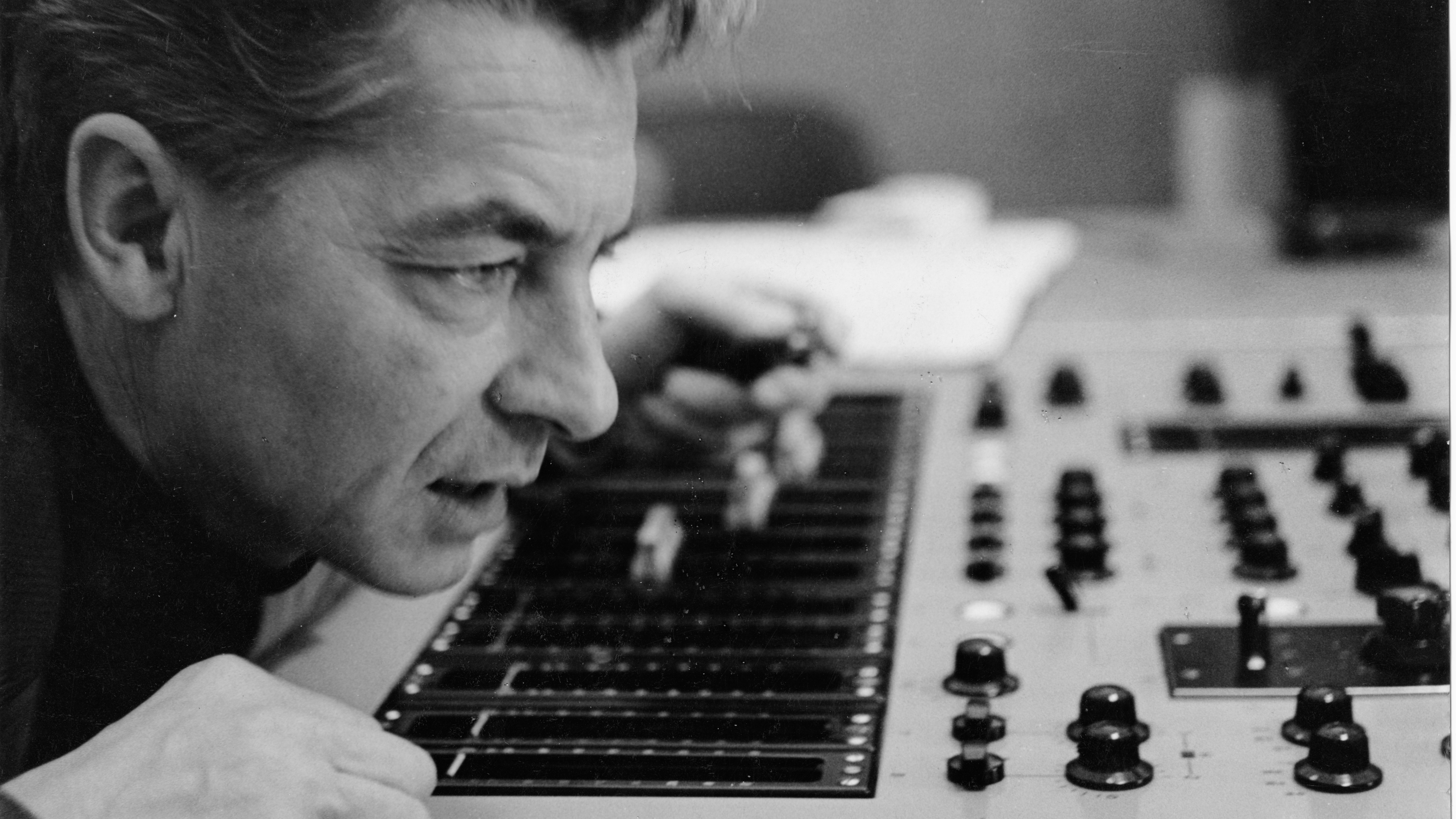 Herbert von Karajan über einem Mischpult gebeugt.