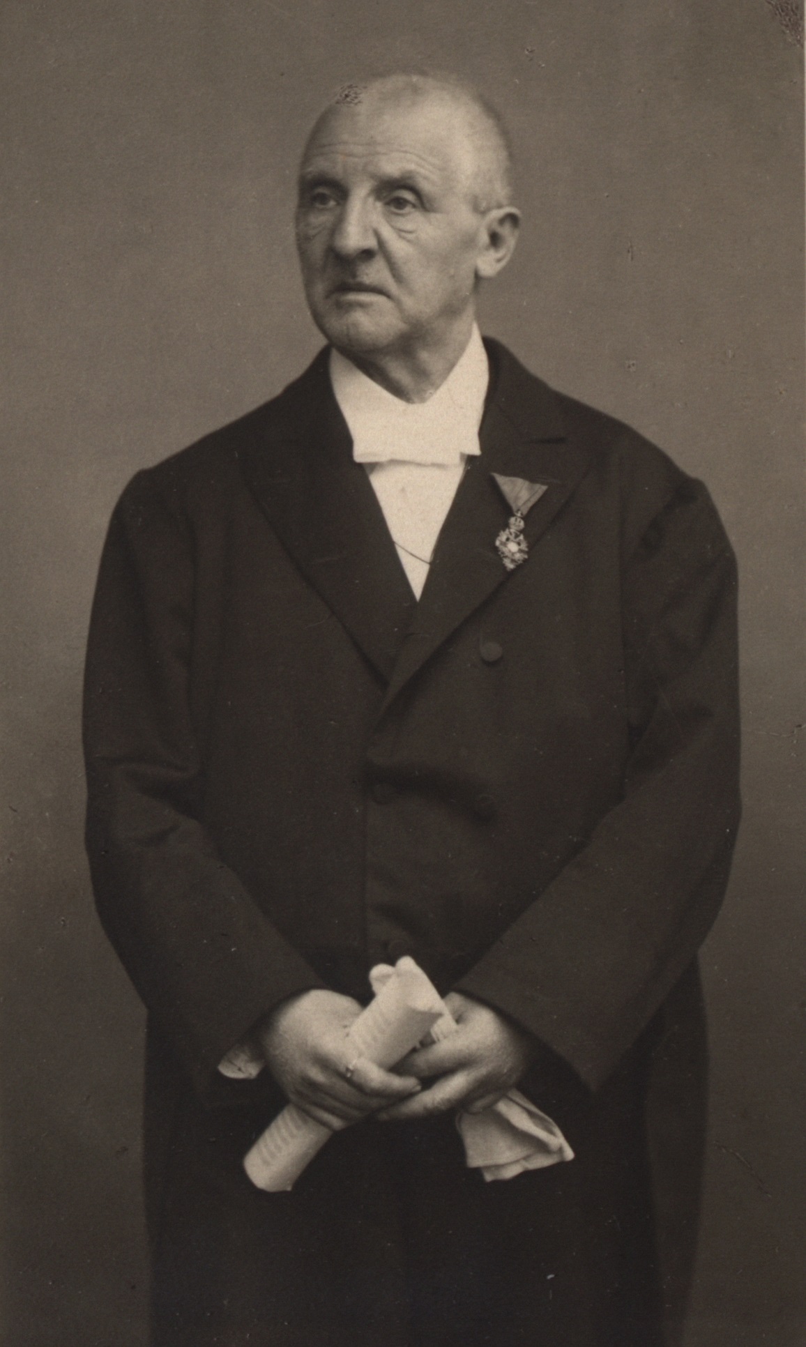 Portrait of Anton Bruckner. He is looking to his right side, holding documents in his hands.